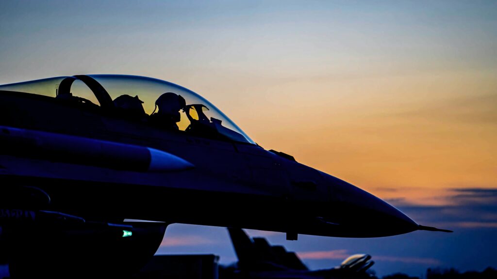 General Dynamics F-16 Fighting Falcon jet silhouette at sunset with vibrant blue and orange sky background Wallpaper
