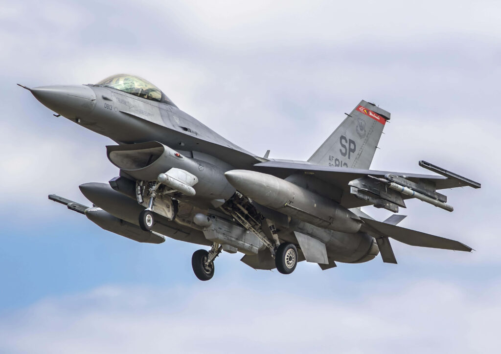 General Dynamics F-16 Fighting Falcon jet in mid-flight with sleek design and cloudy sky background Wallpaper