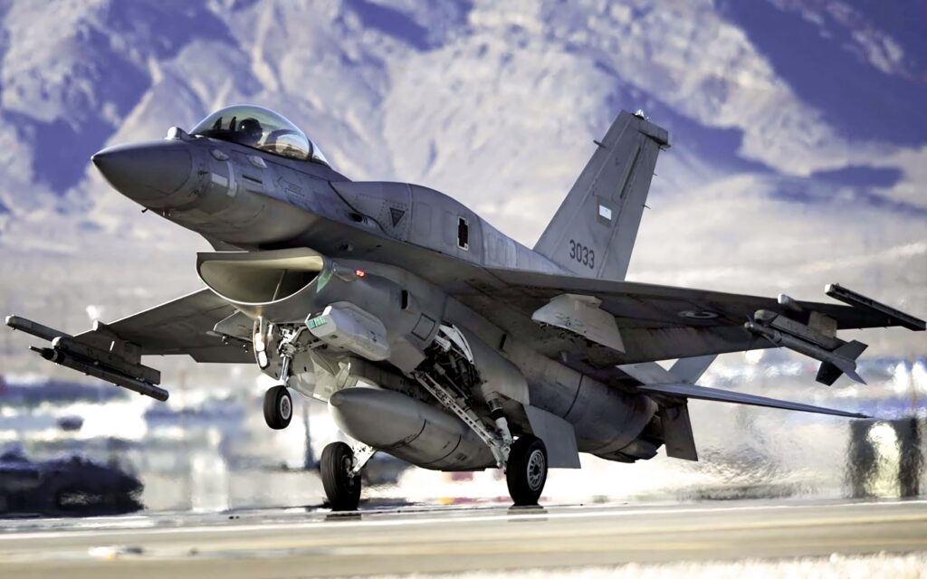 General Dynamics F-16 Fighting Falcon flying over rugged mountains with clear sky background Wallpaper