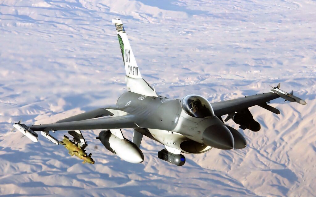 High-resolution F-16 Fighting Falcon jet soaring over desert with sleek design and gray camouflage Wallpaper
