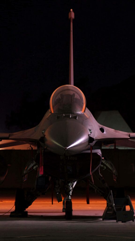 General Dynamics F-16 Fighting Falcon fighter jet highlighted in warm low light against night sky wallpaper