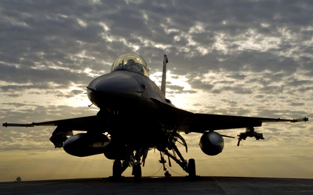 General Dynamics F16 Fighting Falcon on runway at dusk with golden cloudy sky background wallpaper