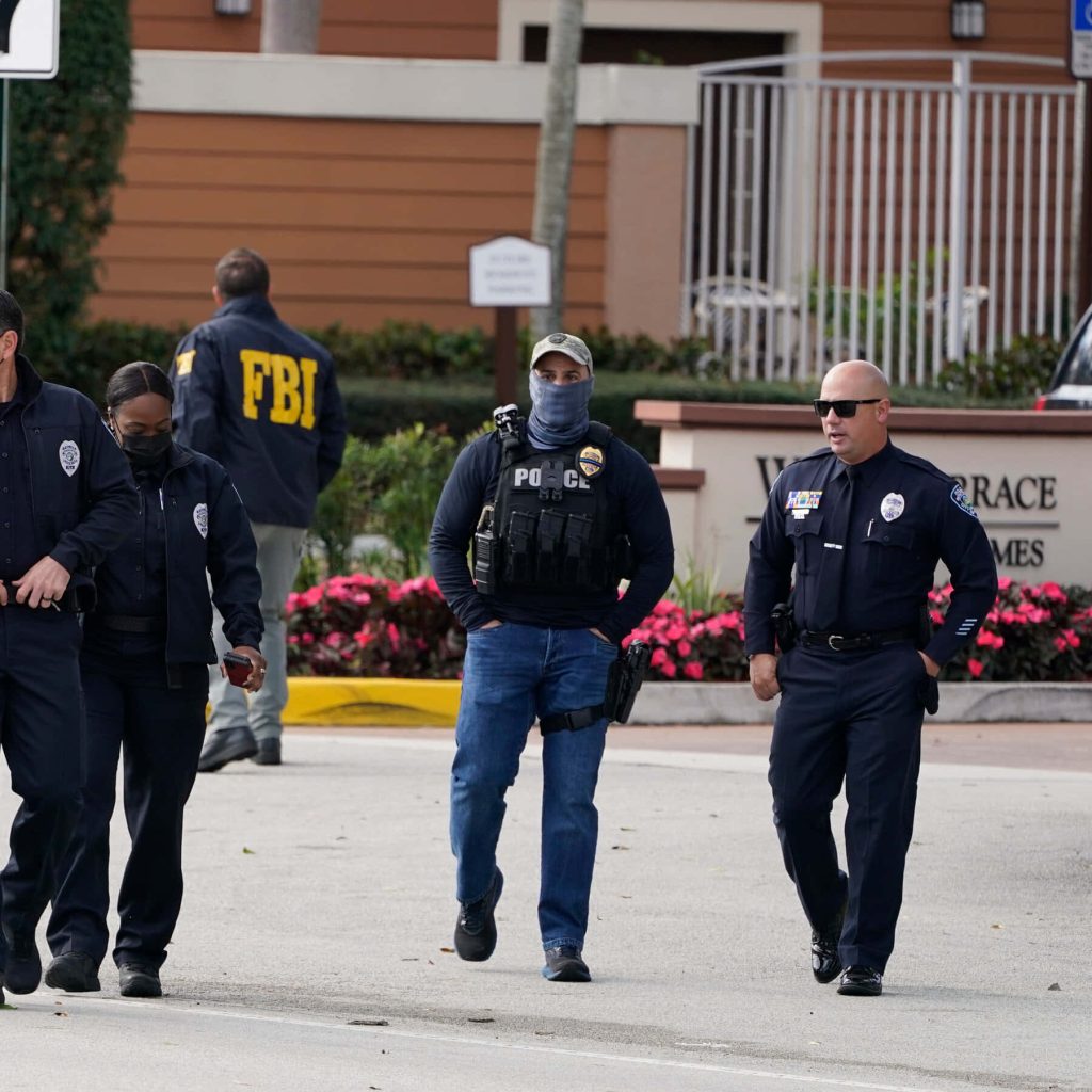 Law enforcement officers and FBI agent in tactical gear patrolling suburban street daytime scene Wallpaper