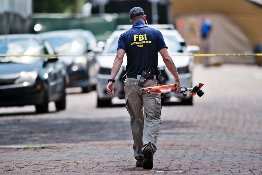 FBI Evidence Response Team member in tactical gear with surveying tools on crime scene street Wallpaper