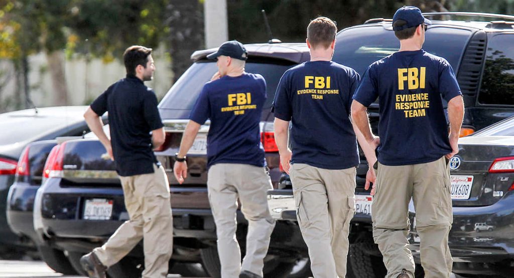 FBI Evidence Response Team agents in navy uniforms walking past black SUVs at crime scene Wallpaper