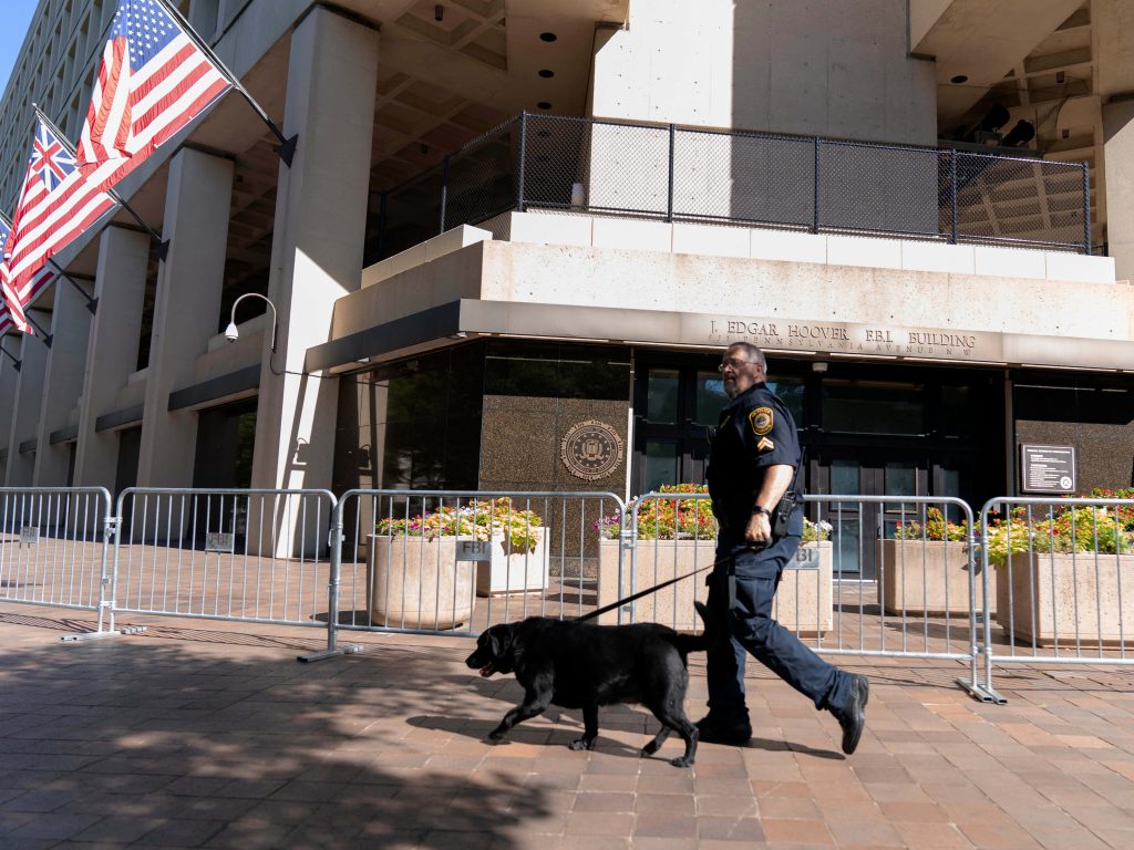 FBI officer with K9 patrol outside J Edgar Hoover FBI Building Washington DC sunny day Wallpaper