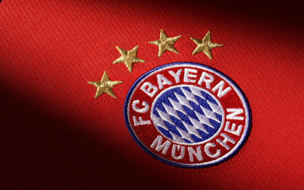 FC Bayern Munich logo patch with four gold stars on vibrant red wallpaper background