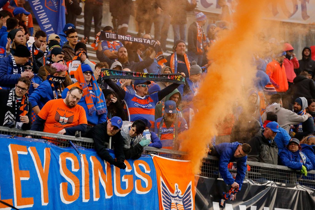 FC Cincinnati fans cheer in The Bailey with orange smoke and blue gear in vibrant MLS match wallpaper