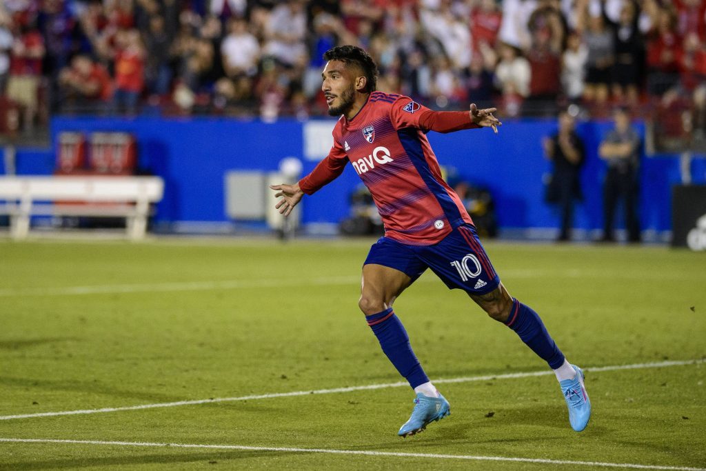 FC Dallas striker Jesús Ferreira celebrates goal in red blue jersey under stadium lights Wallpaper