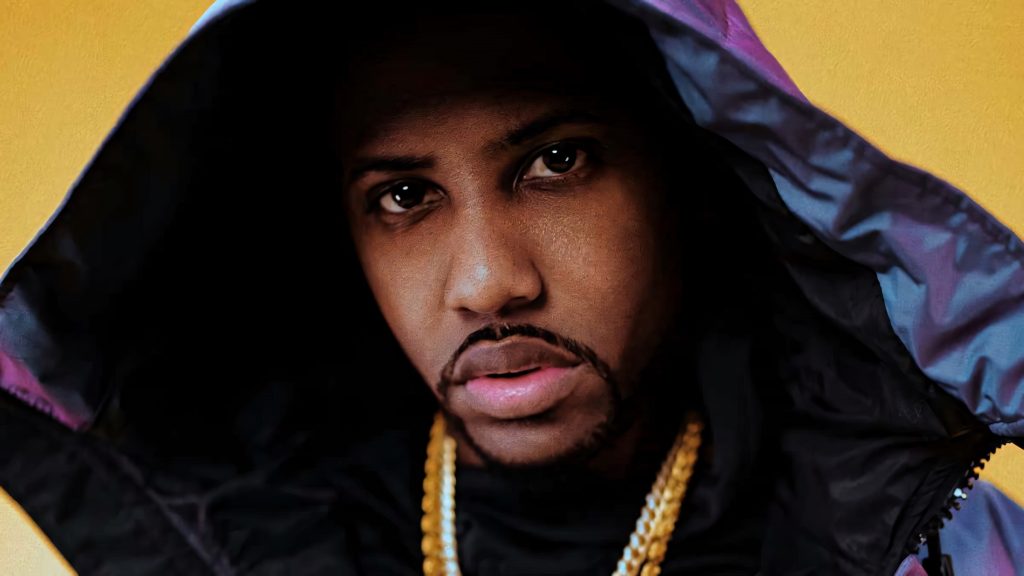 Close-up portrait of rapper Fabolous in hooded jacket with gold chain on yellow background Wallpaper