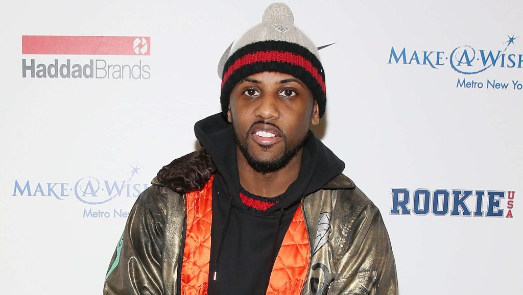 Rapper Fabolous in metallic jacket and striped beanie at Make A Wish event step and repeat backdrop Wallpaper