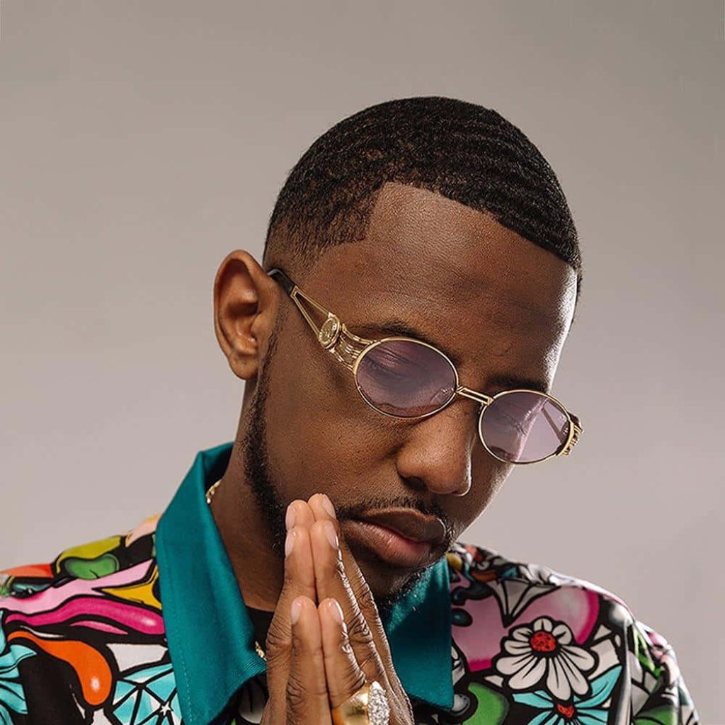 Portrait of rapper Fabolous with gold sunglasses and diamond ring in vibrant shirt on grey background Wallpaper