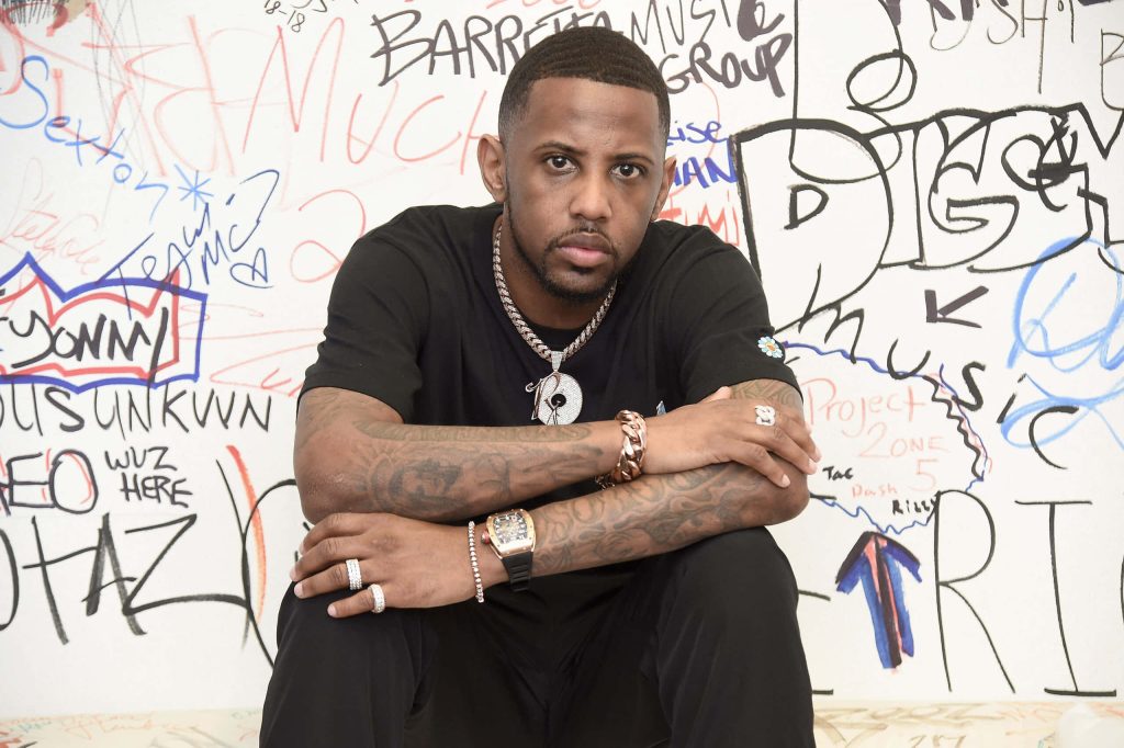 Fabolous rapper with crossed tattooed arms and diamond chains against white graffiti wall Wallpaper