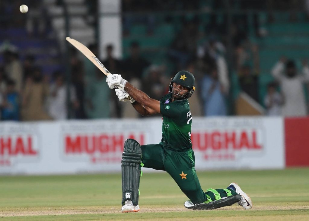 Fakhar Zaman batting sweep shot in dark green Pakistan cricket kit with stadium background Wallpaper