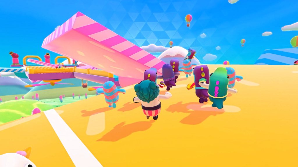 Fall Guys colorful bean characters race on yellow platform with pink see saw and blue sky Wallpaper