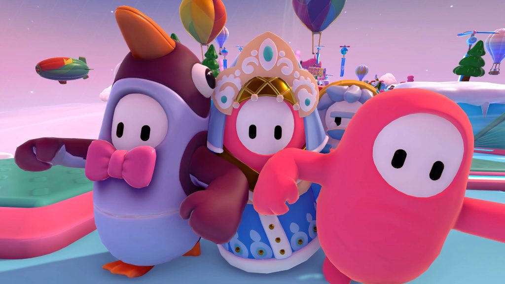 Fall Guys characters racing on icy winter course with hot air balloons in pastel sky wallpaper