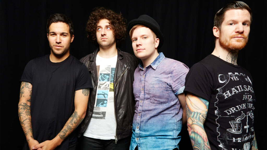 Fall Out Boy band members posing against dark background ready to perform on stage wallpaper