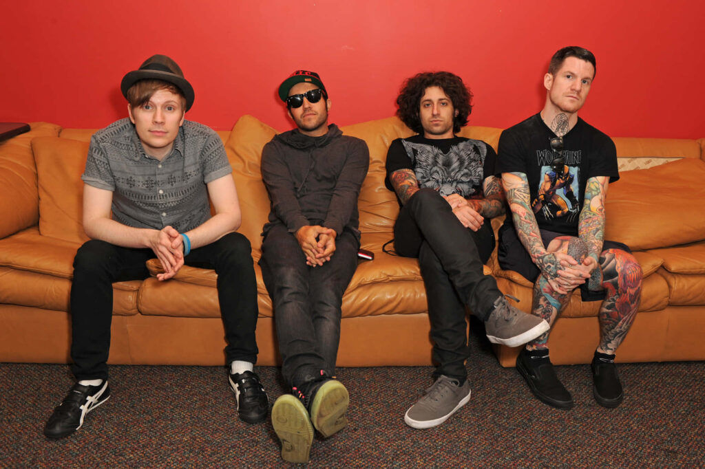 Fall Out Boy band members sitting on tan couch red wall unique styles iconic presence wallpaper