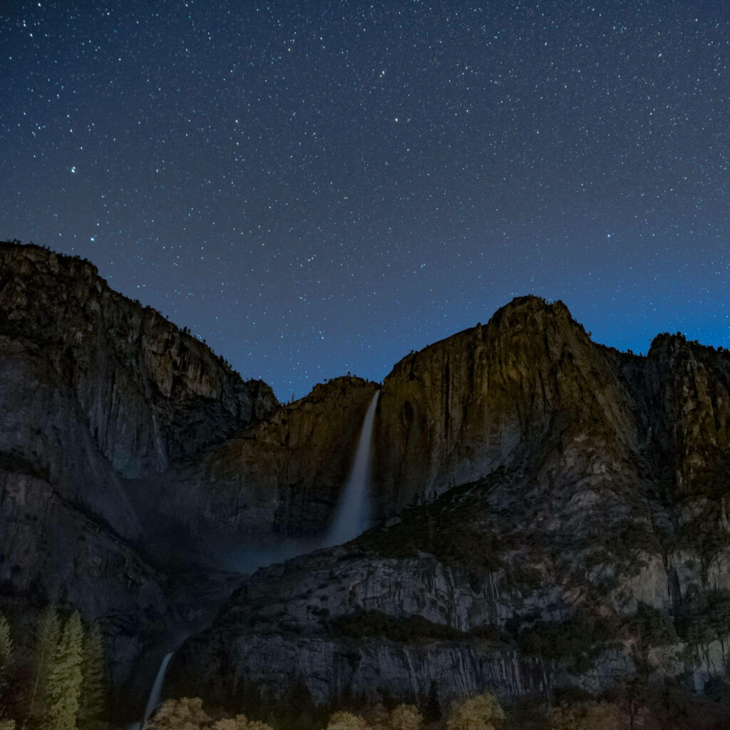 Starry Night Cascade: Mesmerizing Waterfall on Mountain viewed through iPad Pro Wallpaper