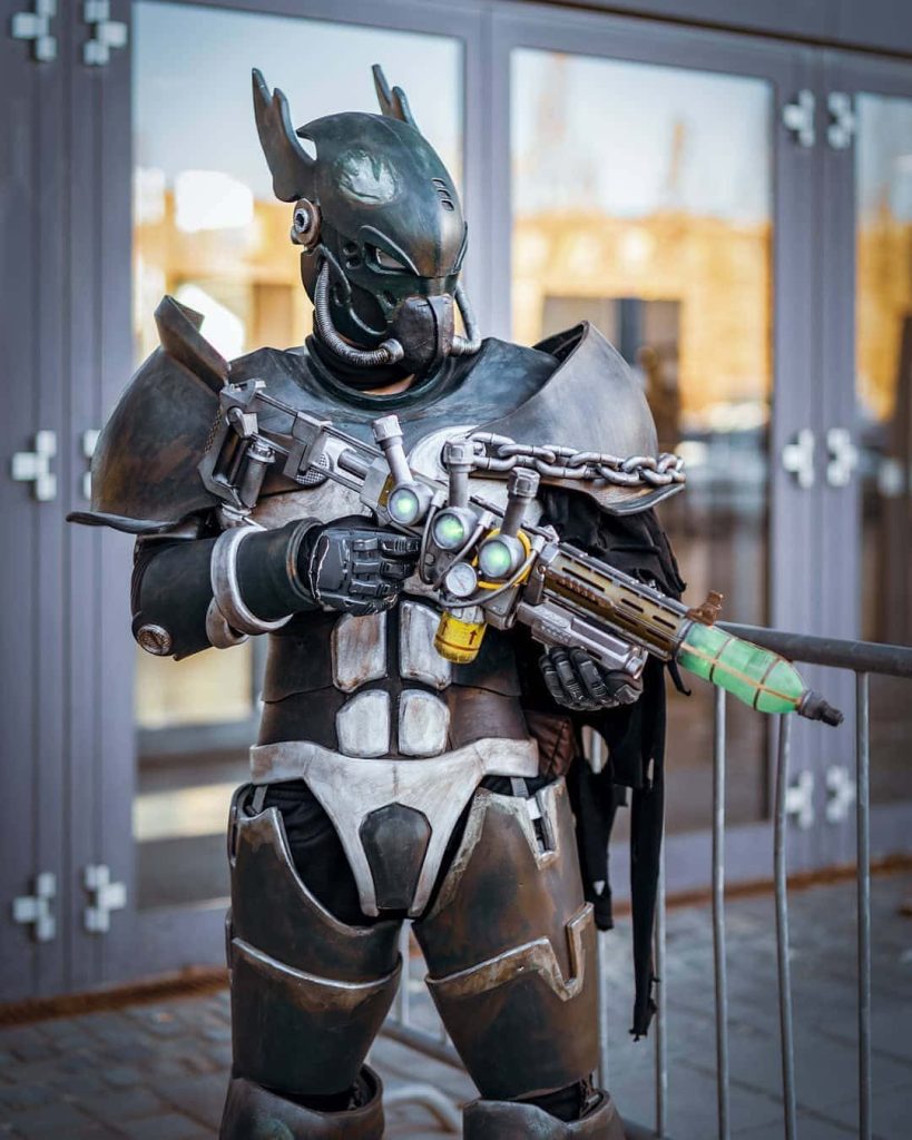 Fallout cosplay in weathered X-01 Power Armor with glowing green Plasma Rifle outdoors urban background Wallpaper