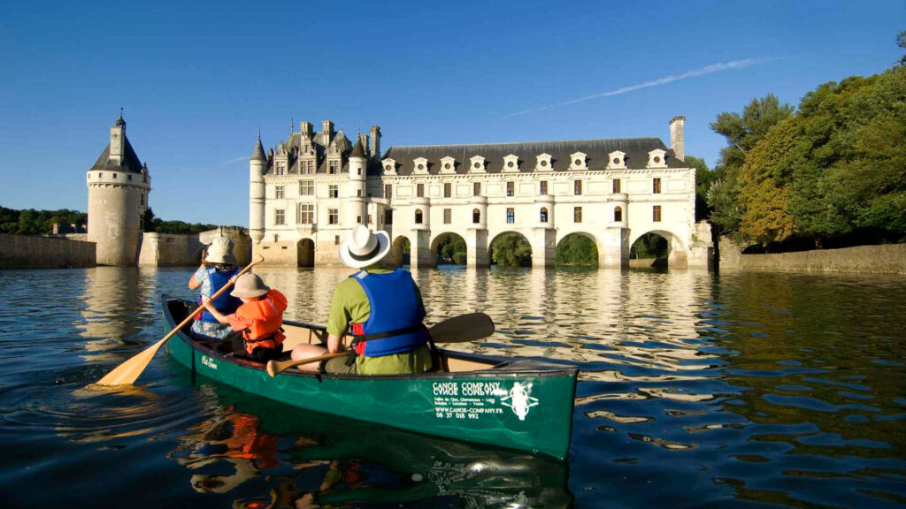 Family boating on calm river with Château de Chenonceau Renaissance arches reflection background Wallpaper