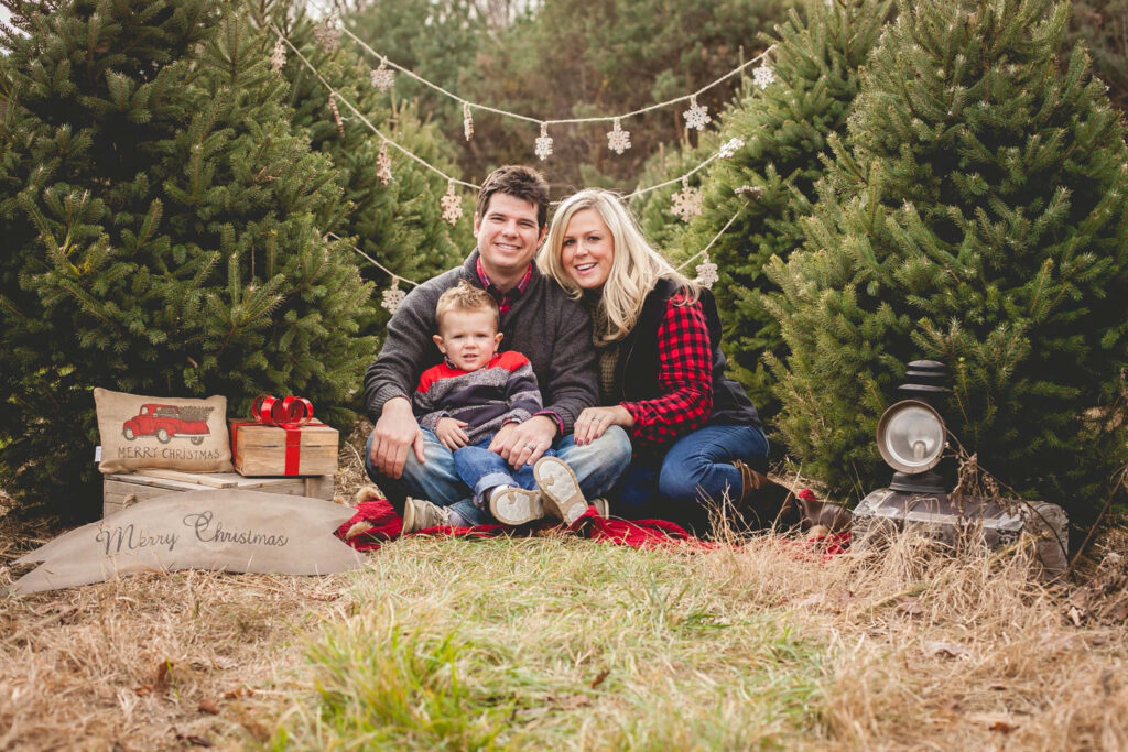 Joyful Family Portrait Amid Christmas Trees & Festive Decor Wallpaper