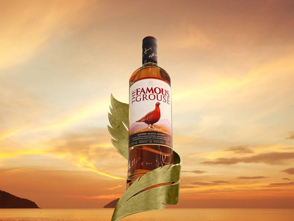 Famous Grouse Blended Scotch Whisky bottle with golden ribbon and amber sunset sea wallpaper