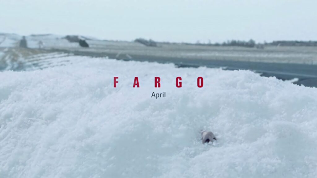 Snowy landscape with gloved hand under snow and bold red Fargo title April release teaser wallpaper
