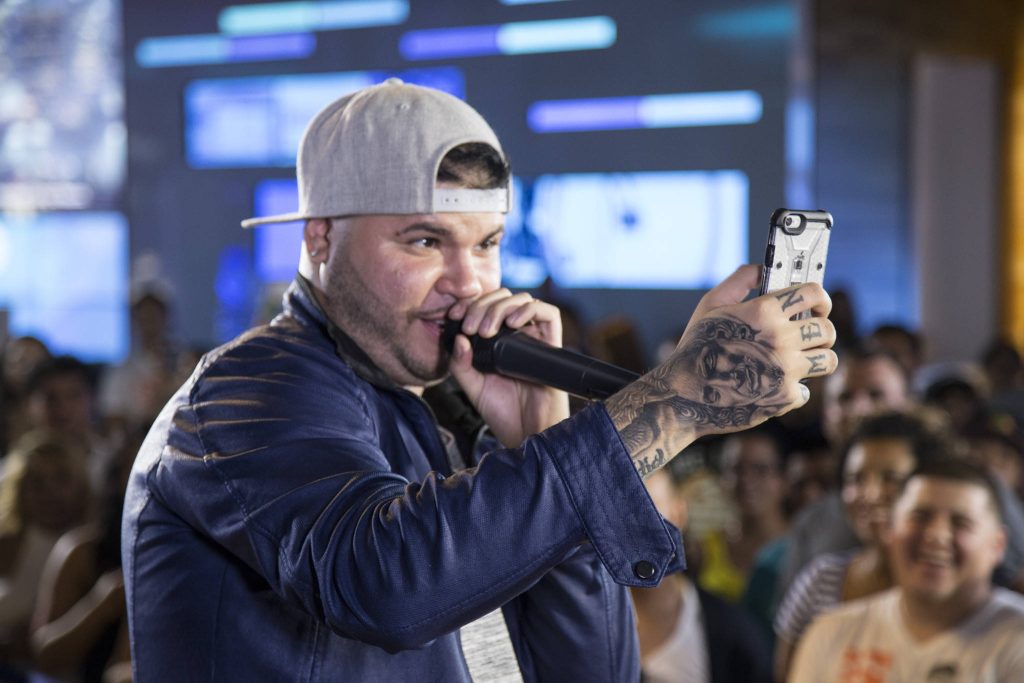 Reggaeton singer Farruko mid-performance holding microphone and taking selfie in blue jacket Wallpaper