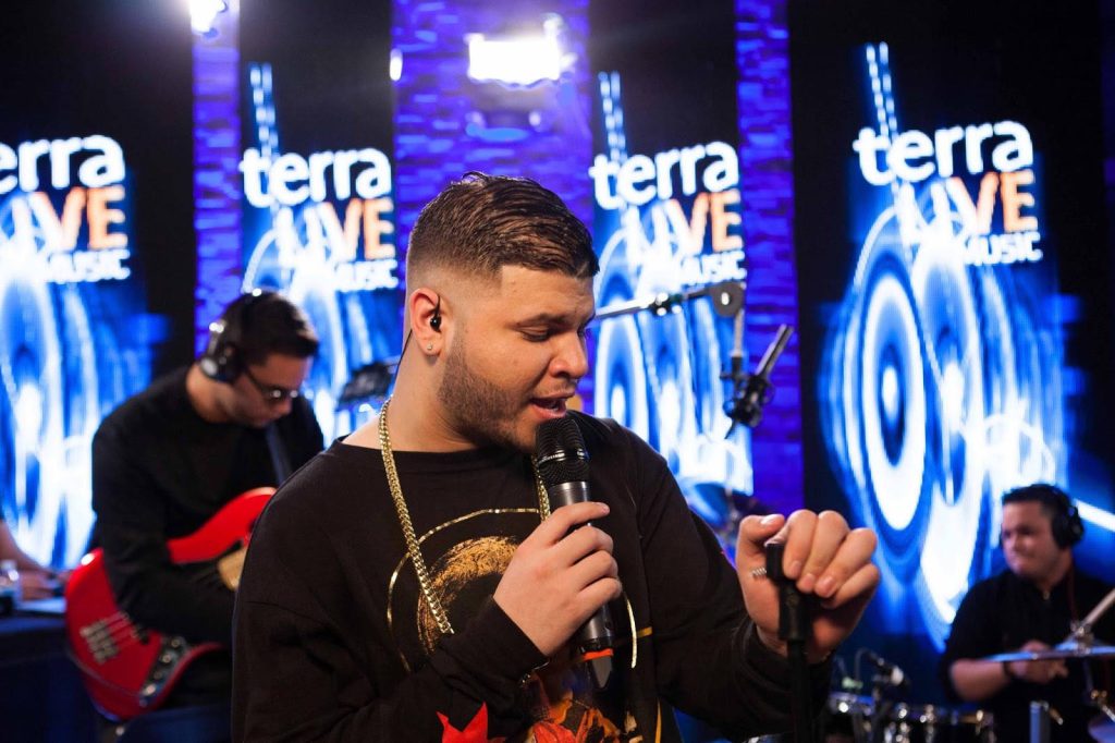 Farruko performing live with intense vocals and blue stage lights at Terra Live Music concert Wallpaper