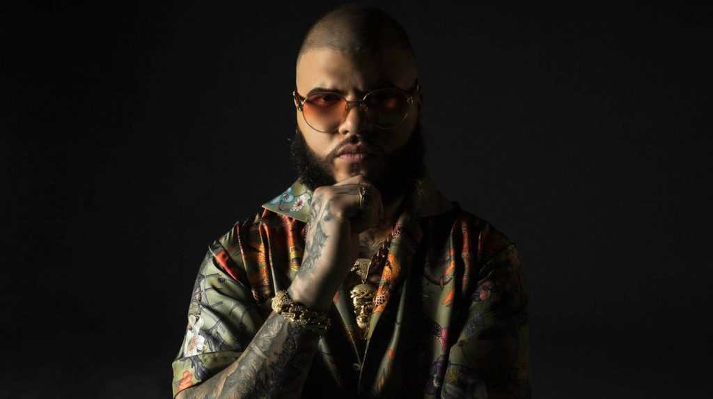 Portrait wallpaper of Puerto Rican artist Farruko in green shirt sunglasses gold jewelry tattoos