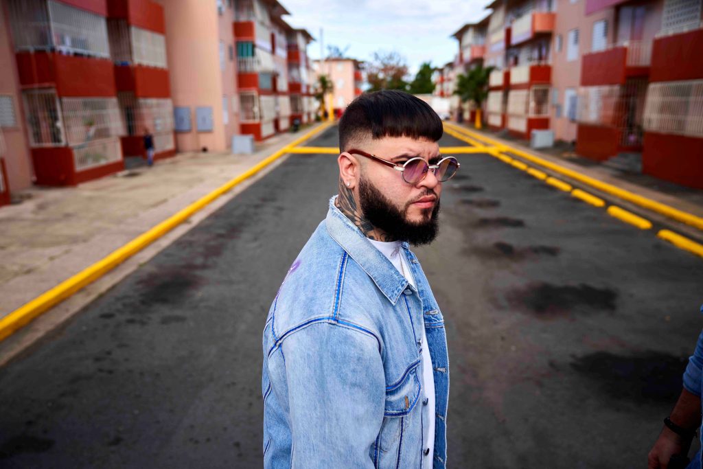 Farruko in light-wash denim jacket and sunglasses urban street style wallpaper background