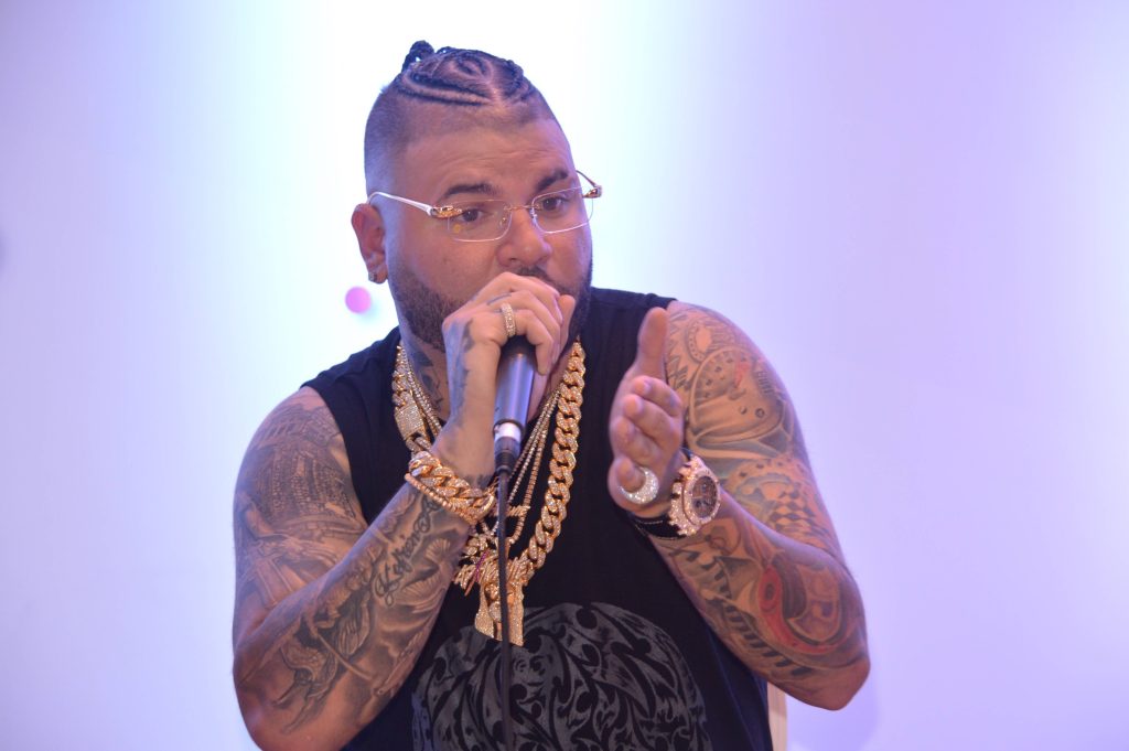 Farruko wallpaper with braided hair gold chains tattoos stylish glasses bright background