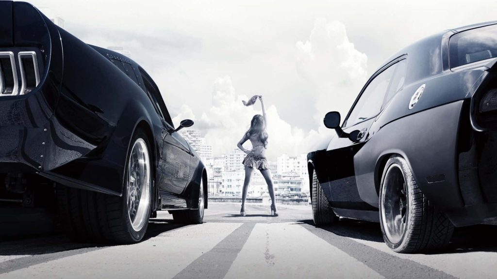 Woman between two black muscle cars street racing cityscape Fast and Furious 9 wallpaper