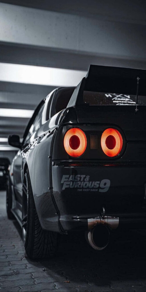Sleek sports car with bold taillights and large spoiler in dim parking garage Fast and Furious 9 Wallpaper
