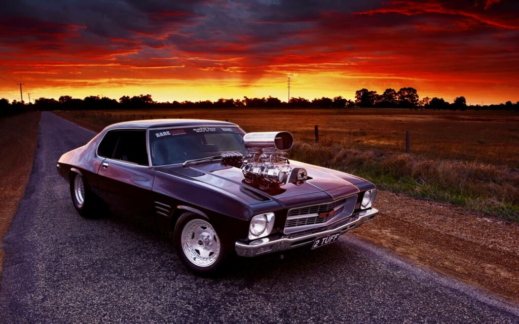 Fast and Furious car on open road at vibrant sunset with dramatic orange and red sky background Wallpaper