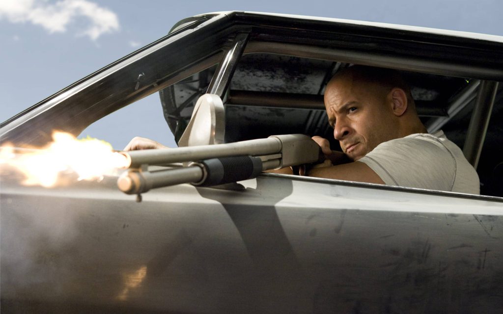 Vin Diesel as Dom Toretto firing shotgun from silver muscle car intense Fast Furious wallpaper