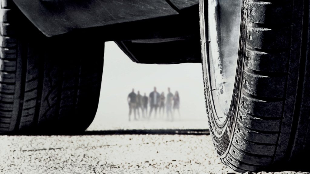 Low-angle Fast and Furious 7 wallpaper with silhouetted cast under car chassis in moody haze