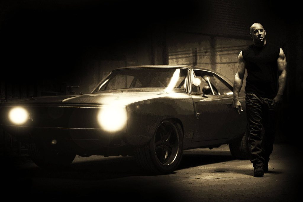 Vin Diesel as Dominic Toretto with classic muscle car and glowing headlights vintage wallpaper
