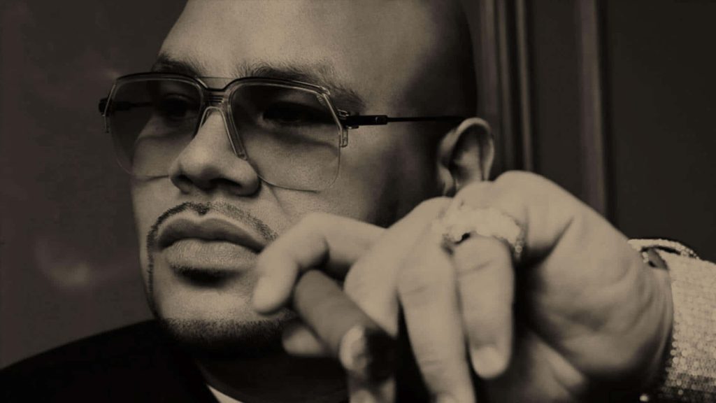 Close-up sepia wallpaper of hip-hop icon Fat Joe with glasses cigar and iced ring