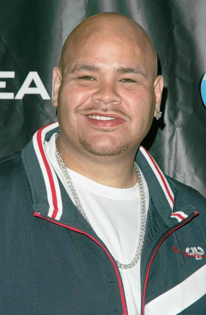 Fat Joe close-up smiling rapper in dark jacket with red accents and silver chain wallpaper background