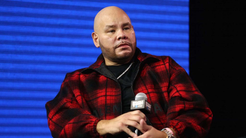 Fat Joe speaking at Revolt Summit in red black plaid jacket bright blue LED background wallpaper