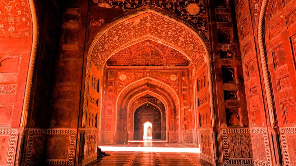 Fatehpur Sikri red sandstone arches with intricate carvings in warm amber light background wallpaper