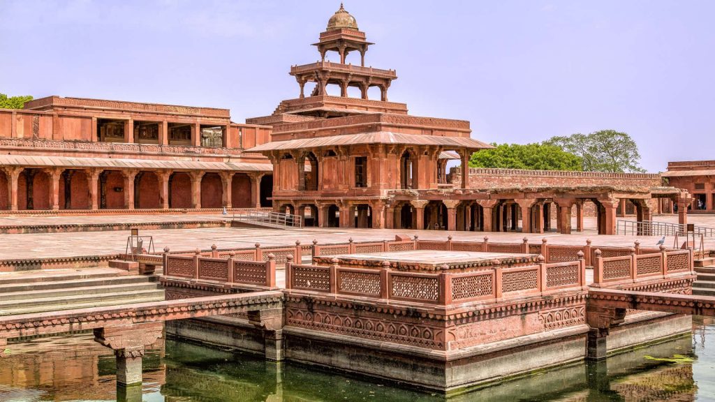 Fatehpur Sikri Panch Mahal red sandstone Mughal architecture with Anup Talao pool under bright sky Wallpaper
