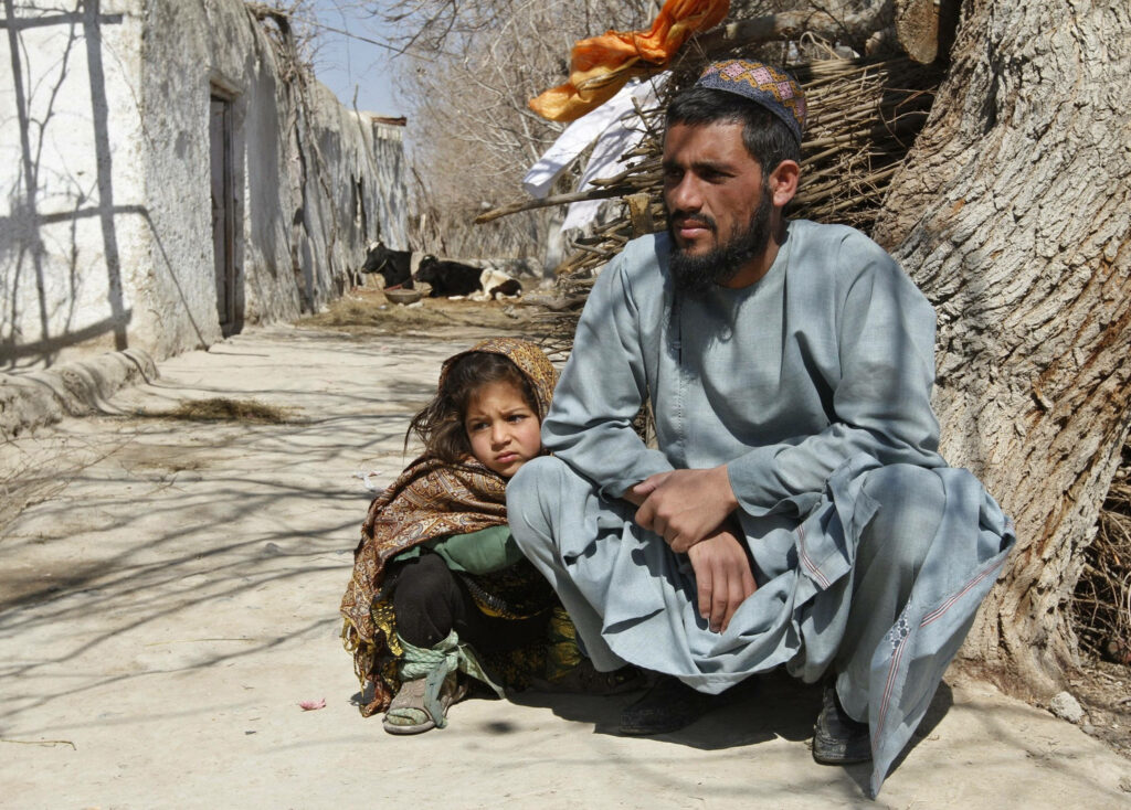 Father and daughter sitting under large tree in rural Afghan village bonding outdoors wallpaper