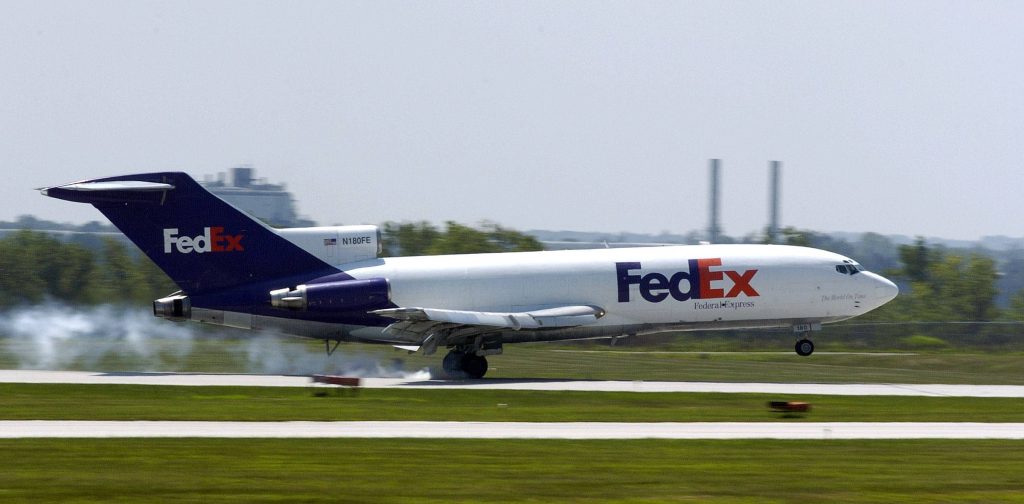 FedEx Boeing 727 cargo plane landing with smoke trails on runway bright daytime sky Wallpaper