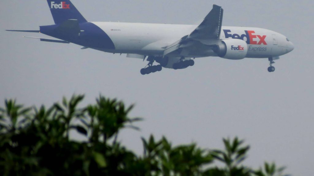 FedEx Express Boeing 777 cargo plane N861FD descending through hazy overcast sky wallpaper
