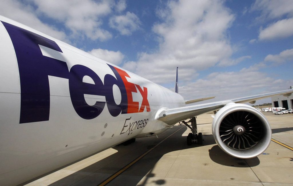 Close-up of FedEx Express cargo plane with clear logo and jet engine on sunny blue sky background Wallpaper