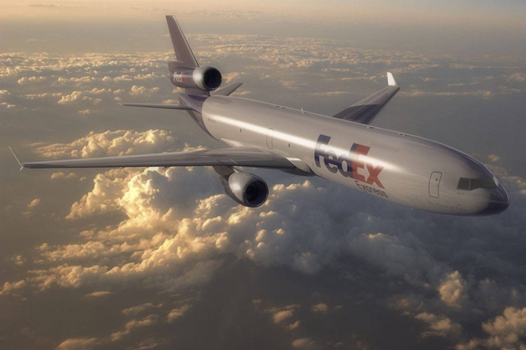 FedEx Express MD-11F cargo jet flying above clouds at sunset photorealistic aviation wallpaper