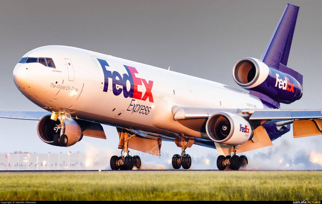 FedEx Express MD-11F cargo plane landing with tire smoke at golden sunset runway wallpaper